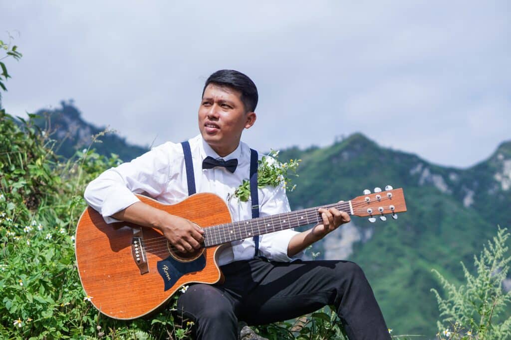 acoustic singer holding guitar on mountain cliff